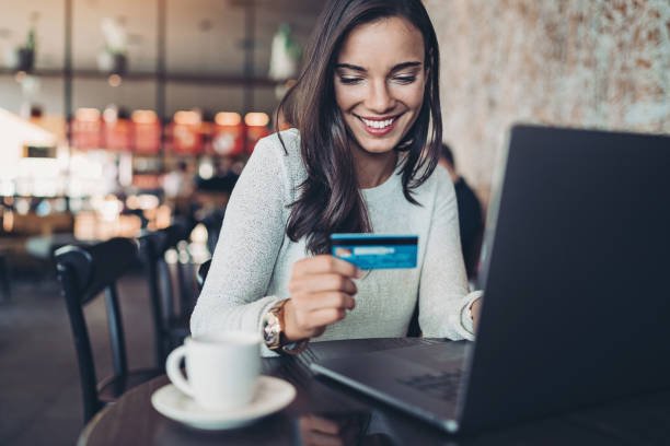 Smiling businesswoman holding a credit card and using laptop in a restaurant